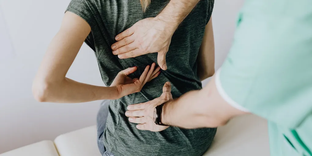 Fisioterapeuta avaliando a postura da coluna lombar de um paciente