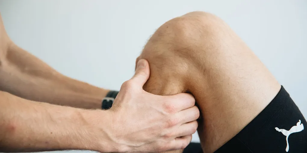 Fisioterapeuta avaliando a mobilidade do joelho de um paciente