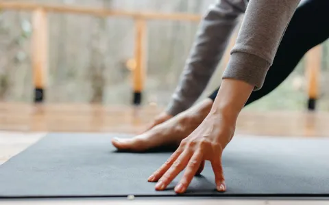 Mãos apoiadas sobre um tapete de exercícios durante um alongamento em quatro apoios