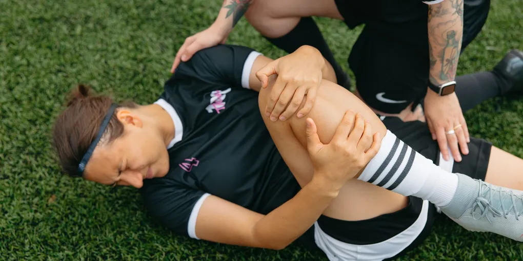 Atleta sendo avaliado por fisioterapeuta após lesão no joelho durante treino