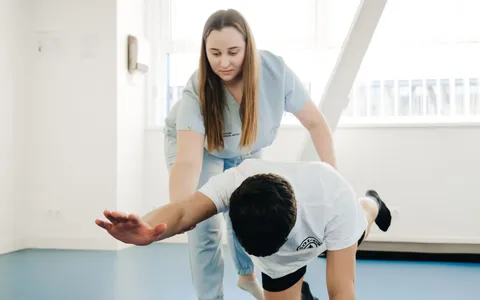 Fisioterapeuta orientando paciente durante exercício de mobilidade em quadrupedia