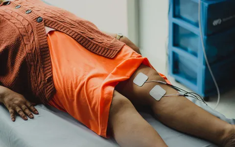 Fisioterapeuta avaliando a mobilidade do joelho de um paciente após cirurgia de prótese