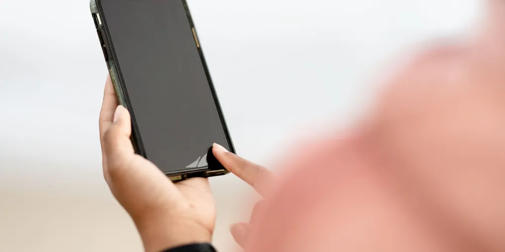 Pessoa olhando para o celular com o pescoço inclinado para baixo