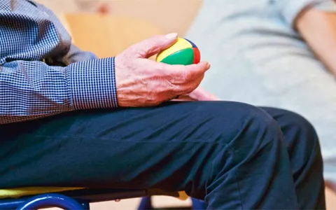 Fisioterapeuta auxiliando paciente idoso em exercício de equilíbrio