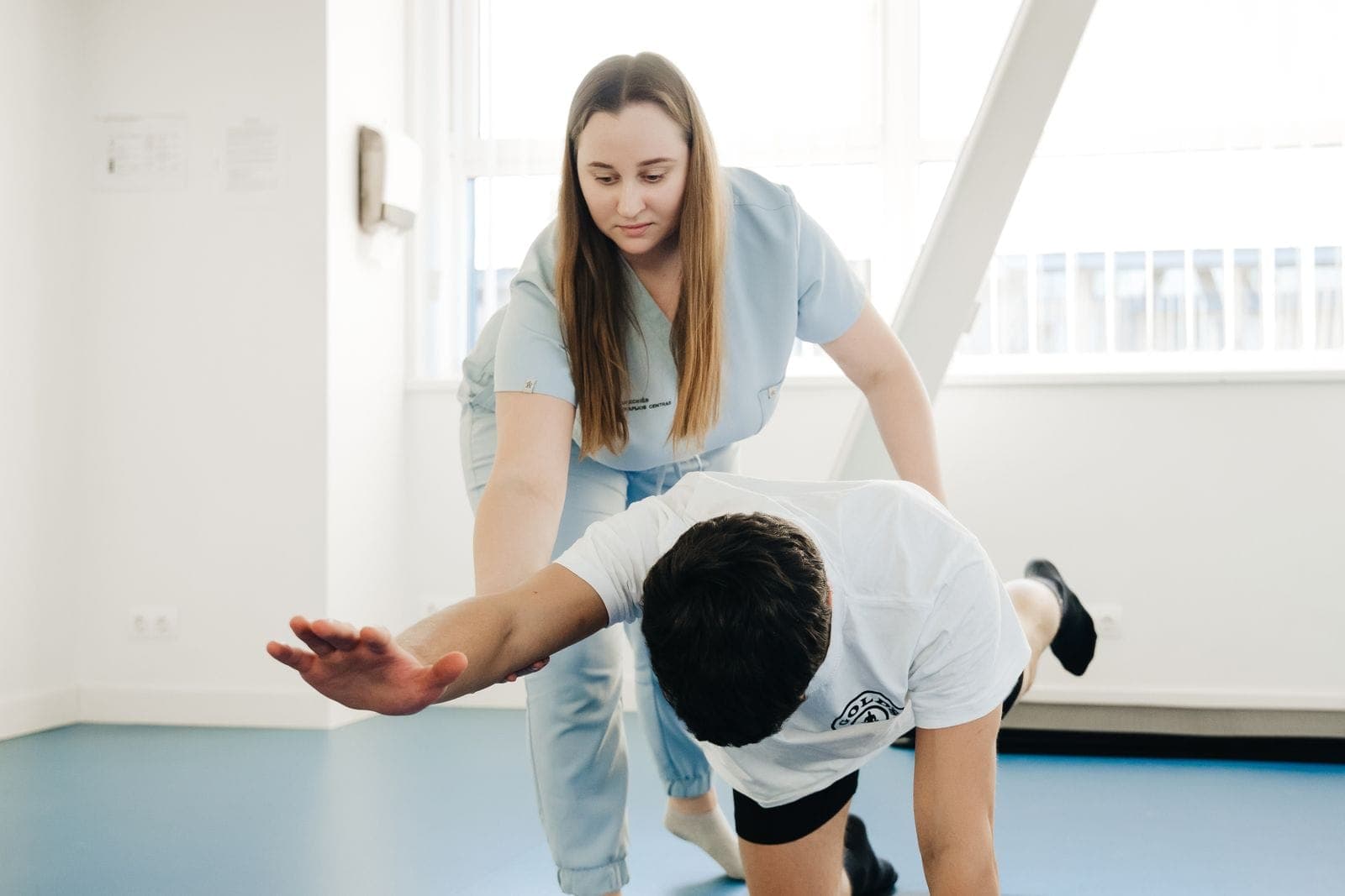 Fisioterapeuta orientando paciente durante exercício de mobilidade em quadrupedia