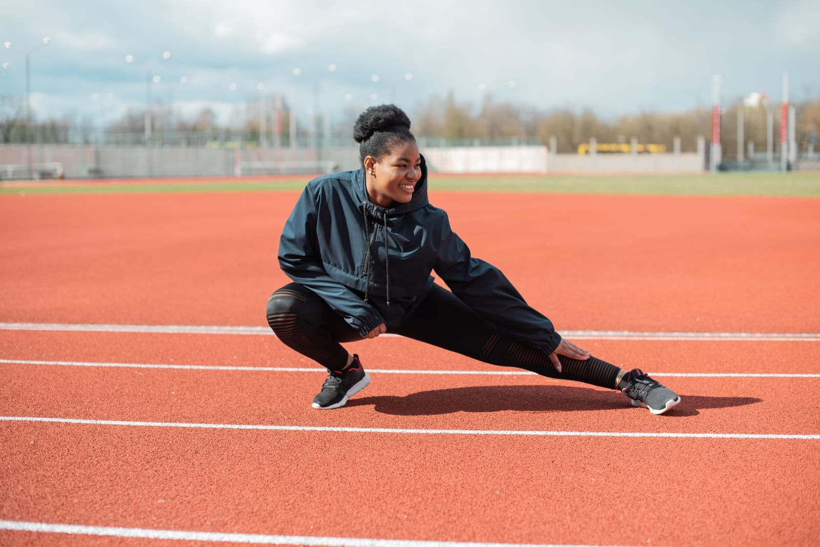 Atleta alongando a perna em pista de atletismo ao ar livre